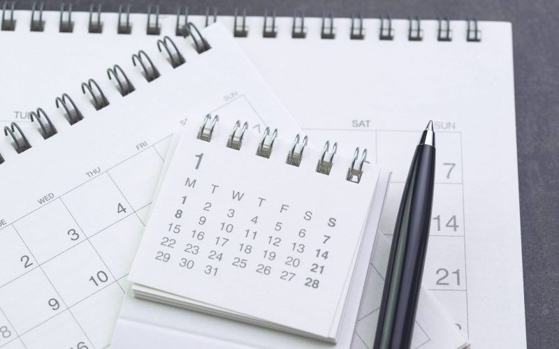 Calendar planning with pen on black background using as date orgainizer or year plan concept.